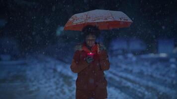 Young African Woman Standing on Street at Night During Snow Fall with Umbrella video