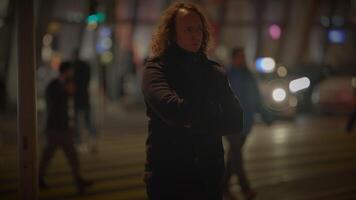 A woman with crossed arms stands on a city street at midnight video