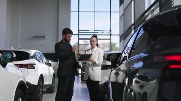 competente carro revendedor usando tábua para trabalhos com clientes às showroom. falando com Gerente enquanto comprando carro às concessionária Centro. video