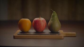 Three fruits are arranged on a wooden cutting board video