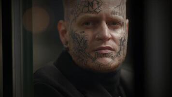 intimidante disidente rebelde hombre con cabeza y cara tatuajes en provocador estilo video
