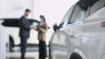 gerente de un coche concesión sostiene tableta para firma y da llave a un cliente. un masculino barbado cliente elegir coche a concesión con el ayuda de auto vendedor. gerente en auto concesión video