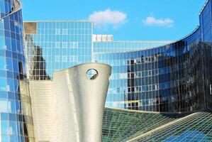 Structural glass wall reflecting blue sky. Abstract modern architecture fragment photo