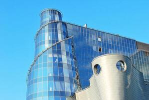 Structural glass wall reflecting blue sky. Abstract modern architecture fragment photo