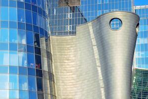 Structural glass wall reflecting blue sky. Abstract modern architecture fragment photo