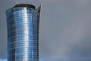 Structural glass wall reflecting blue sky. Abstract modern architecture fragment. photo