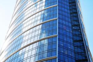 Structural glass wall reflecting blue sky. Abstract modern architecture fragment. photo