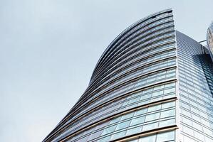 Structural glass wall reflecting blue sky. Abstract modern architecture fragment. photo