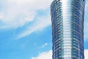 Structural glass wall reflecting blue sky. Abstract modern architecture fragment. photo