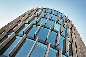 Glass building with transparent facade of the building and blue sky. Structural glass wall reflecting blue sky. Abstract modern architecture fragment. Contemporary architectural background. photo