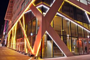 Fragment of the glass facade of a modern corporate building at night. Modern glass office in city. Big glowing windows in modern office buildings at night, in rows of windows light shines. photo