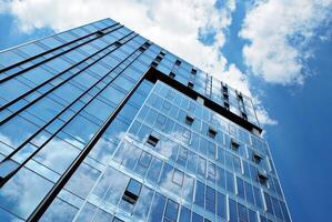 Glass building with transparent facade of the building and blue sky. Structural glass wall reflecting blue sky. Abstract modern architecture fragment. Contemporary architectural background. photo