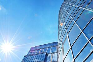 Glass building with transparent facade of the building and blue sky. Structural glass wall reflecting blue sky. Abstract modern architecture fragment. Contemporary architectural background. photo