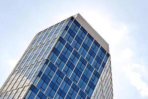 Glass building with transparent facade of the building and blue sky. Structural glass wall reflecting blue sky. Abstract modern architecture fragment. Contemporary architectural background. photo