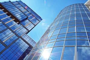 Glass building with transparent facade of the building and blue sky. Structural glass wall reflecting blue sky. Abstract modern architecture fragment. Contemporary architectural background. photo