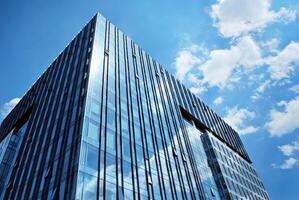 Glass building with transparent facade of the building and blue sky. Structural glass wall reflecting blue sky. Abstract modern architecture fragment. Contemporary architectural background. photo