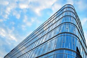 Glass building with transparent facade of the building and blue sky. Structural glass wall reflecting blue sky. Abstract modern architecture fragment. Contemporary architectural background. photo