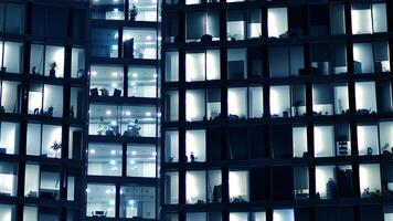 fragmento de el vaso fachada de un moderno corporativo edificio a noche. moderno vaso oficina en ciudad. grande brillante ventanas en moderno oficina edificios a noche, en filas de ventanas ligero brilla foto