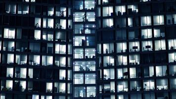 fragmento de el vaso fachada de un moderno corporativo edificio a noche. moderno vaso oficina en ciudad. grande brillante ventanas en moderno oficina edificios a noche, en filas de ventanas ligero brilla foto