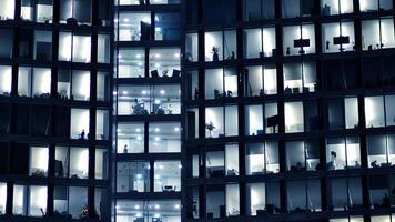 fragmento de el vaso fachada de un moderno corporativo edificio a noche. moderno vaso oficina en ciudad. grande brillante ventanas en moderno oficina edificios a noche, en filas de ventanas ligero brilla foto