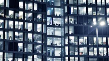 fragmento de el vaso fachada de un moderno corporativo edificio a noche. moderno vaso oficina en ciudad. grande brillante ventanas en moderno oficina edificios a noche, en filas de ventanas ligero brilla foto