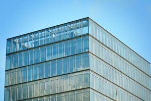 Glass building with transparent facade of the building and blue sky. Structural glass wall reflecting blue sky. Abstract modern architecture fragment. Contemporary architectural background. photo