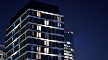 brillante ventanas de el de muchos pisos edificio en noche. ver de moderno residencial edificio en centro. foto
