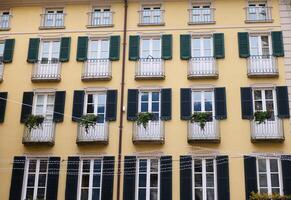 Facades of a house with beautiful balconies decorated with plants in the city center of Italian Como in Lombardy photo