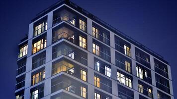 Glowing windows of the multi-storey building in night. View of modern residential building in downtown. photo