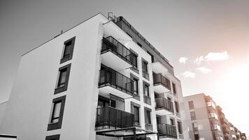 Fragment of the building's facade with windows and balconies. Modern apartment buildings on a sunny day. Facade of a modern residential building. Black and white. photo