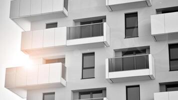 Fragment of the building's facade with windows and balconies. Modern apartment buildings on a sunny day. Facade of a modern residential building. Black and white. photo