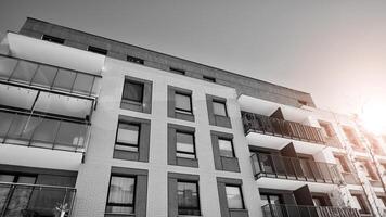 Fragment of the building's facade with windows and balconies. Modern apartment buildings on a sunny day. Facade of a modern residential building. Black and white. photo