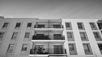 Fragment of the building's facade with windows and balconies. Modern apartment buildings on a sunny day. Facade of a modern residential building. Black and white. photo