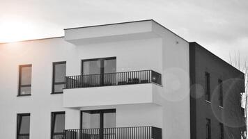 Fragment of the building's facade with windows and balconies. Modern apartment buildings on a sunny day. Facade of a modern residential building. Black and white. photo