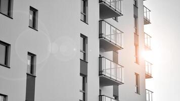 Fragment of the building's facade with windows and balconies. Modern apartment buildings on a sunny day. Facade of a modern residential building. Black and white. photo