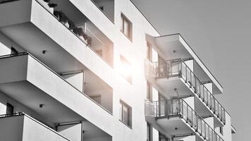 Fragment of the building's facade with windows and balconies. Modern apartment buildings on a sunny day. Facade of a modern residential building. Black and white. photo