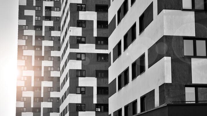 Fragment of the building's facade with windows and balconies. Modern apartment buildings on a sunny day. Facade of a modern residential building. Black and white.
