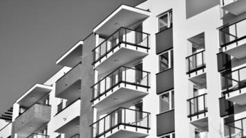 Fragment of the building's facade with windows and balconies. Modern apartment buildings on a sunny day. Facade of a modern residential building. Black and white. photo