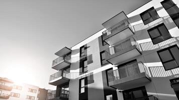 Fragment of the building's facade with windows and balconies. Modern apartment buildings on a sunny day. Facade of a modern residential building. Black and white. photo