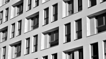 Fragment of the building's facade with windows and balconies. Modern apartment buildings on a sunny day. Facade of a modern residential building. Black and white. photo