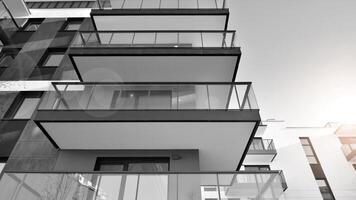 Fragment of the building's facade with windows and balconies. Modern apartment buildings on a sunny day. Facade of a modern residential building. Black and white. photo