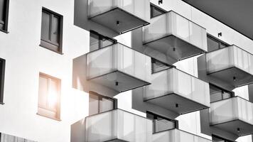 Fragment of the building's facade with windows and balconies. Modern apartment buildings on a sunny day. Facade of a modern residential building. Black and white. photo