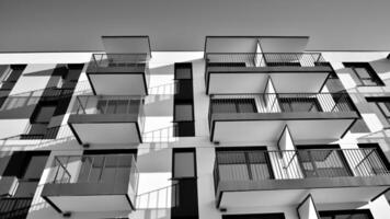 Fragment of the building's facade with windows and balconies. Modern apartment buildings on a sunny day. Facade of a modern residential building. Black and white. photo