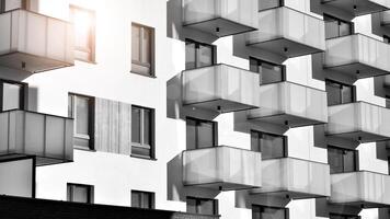 Fragment of the building's facade with windows and balconies. Modern apartment buildings on a sunny day. Facade of a modern residential building. Black and white. photo