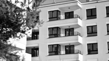 Fragment of the building's facade with windows and balconies. Modern apartment buildings on a sunny day. Facade of a modern residential building. Black and white. photo