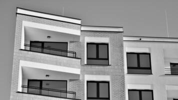 Fragment of the building's facade with windows and balconies. Modern apartment buildings on a sunny day. Facade of a modern residential building. Black and white. photo