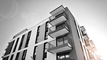 Fragment of the building's facade with windows and balconies. Modern apartment buildings on a sunny day. Facade of a modern residential building. Black and white. photo