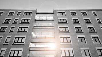Fragment of the building's facade with windows and balconies. Modern apartment buildings on a sunny day. Facade of a modern residential building. Black and white. photo