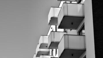 Fragment of the building's facade with windows and balconies. Modern apartment buildings on a sunny day. Facade of a modern residential building. Black and white. photo