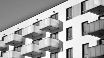 Fragment of the building's facade with windows and balconies. Modern apartment buildings on a sunny day. Facade of a modern residential building. Black and white. photo